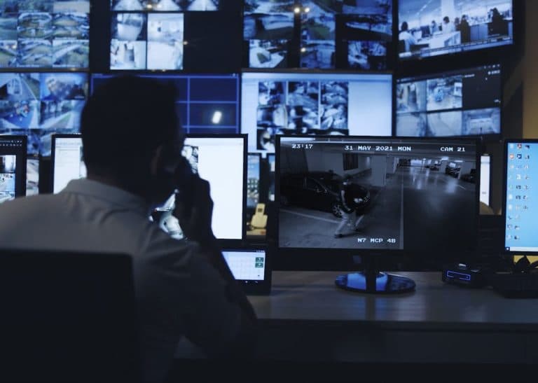 Security operator monitoring multiple video feeds in a control room.