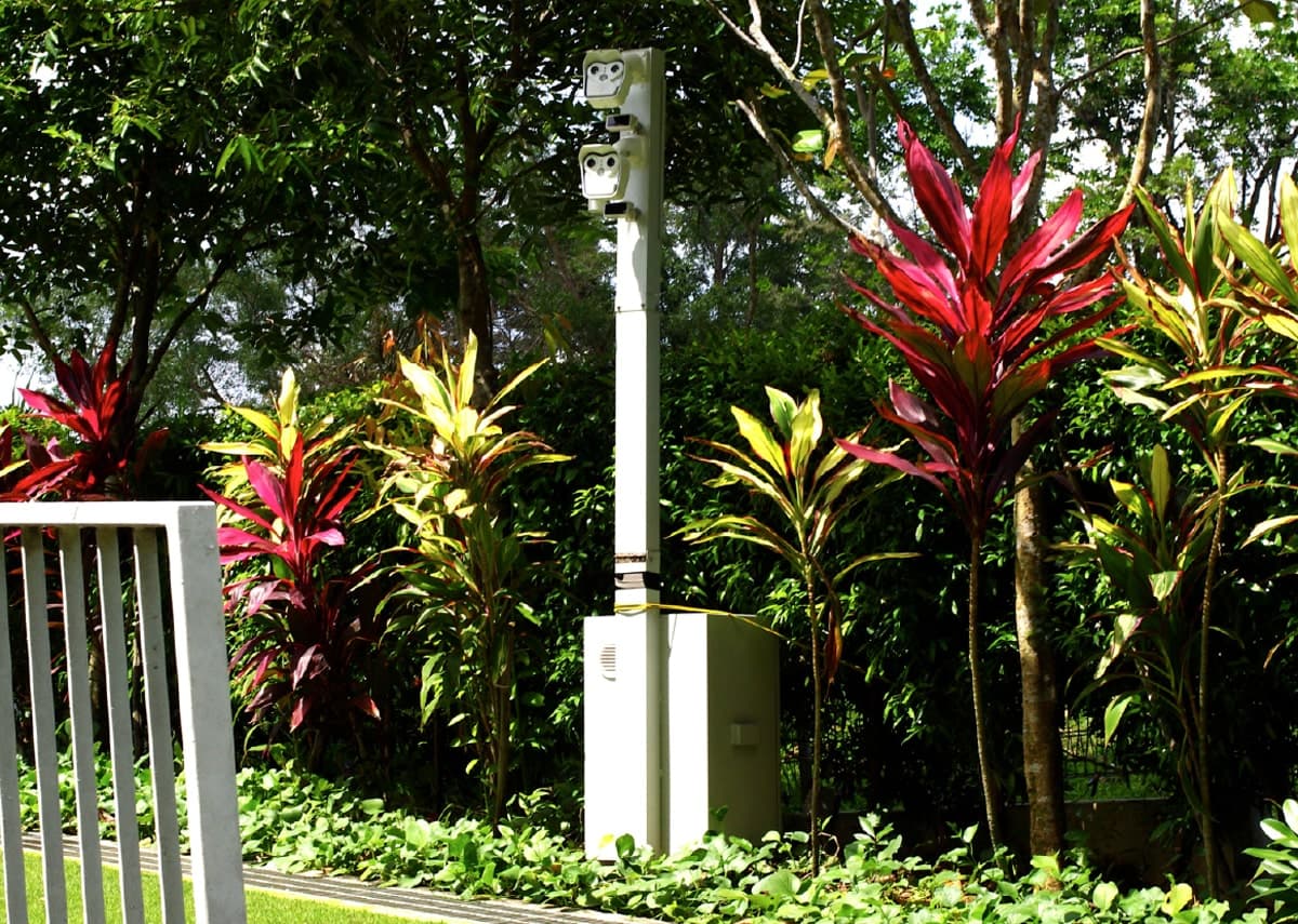 Mobile surveillance pole deployed in a landscaped outdoor environment.