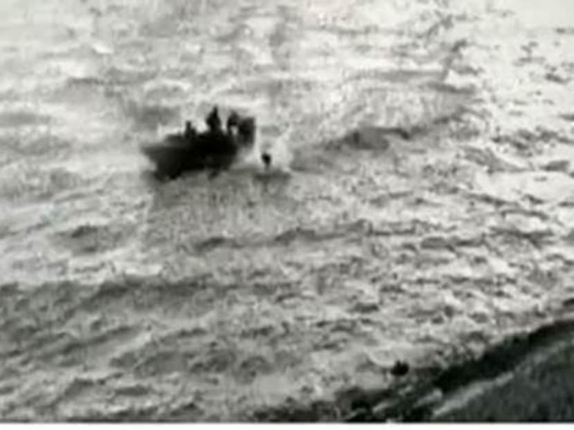 Four men at the shoreline off Tuas reclaimed land.