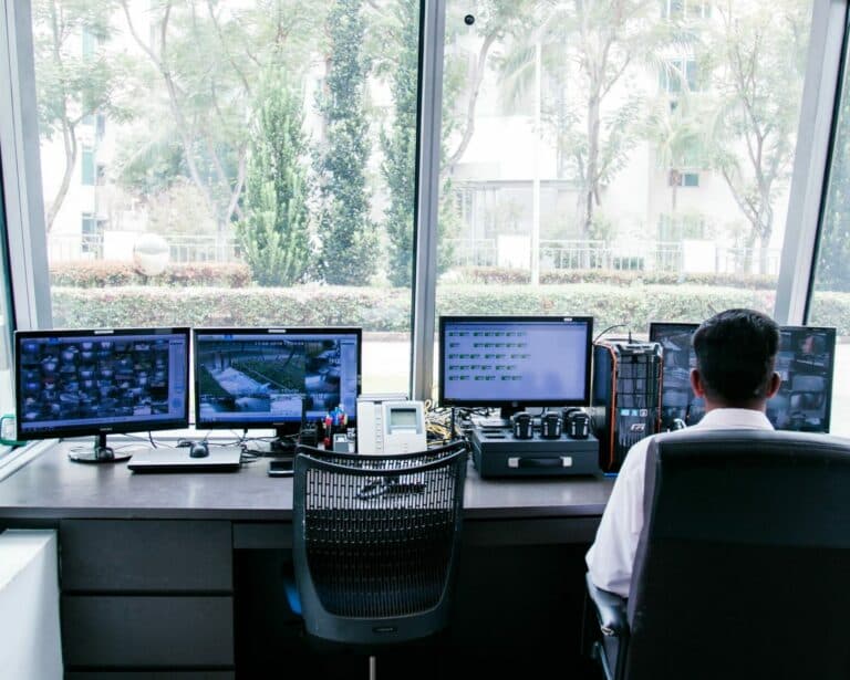 Security officer managing surveillance systems from a workstation.